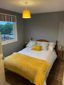 a bedroom with a bed with a yellow blanket on it at 180 River View Cabin in Caeathro