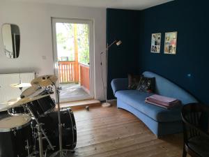 a living room with a blue couch and a drum set at Charmante Unterkunft ohne Küche in Niestetal bei Kassel in Niestetal