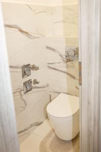 a white toilet in a bathroom with marble walls at Berzsenyi Apartmanház in Kaposvár