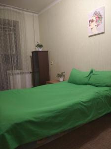 łóżko z zielonym kocem na górze w obiekcie Міні Готель , Кімнати в квартирі - під ключ w Kijowie