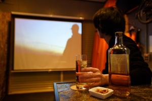 Un uomo seduto a un tavolo con un drink e una bottiglia di 一棟貸し平戸俺んち a Hirado
