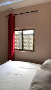 1 dormitorio con ventana y cortina roja en CISFOP en Abomey-Calavi