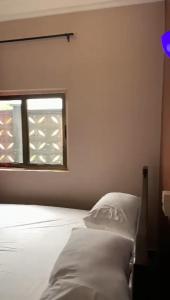 1 dormitorio con cama blanca y ventana en CISFOP en Abomey-Calavi