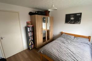 a bedroom with a bed and a wooden cabinet at MODERN 1 Bedroom Ground Floor Flat in London