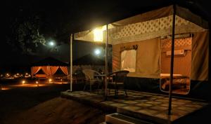 a tent with two chairs and a table at night at Bundeli Resorts in Rājgarh