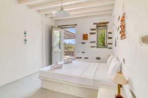 a white bedroom with a bed and a window at Great house w/ BBQ in Paros in Santa Maria