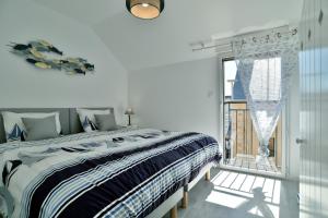 ein weißes Schlafzimmer mit einem großen Bett und einem Fenster in der Unterkunft Les Flots de PortMer in Cancale