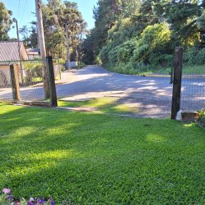 a fence in the grass next to a street at Casa Encantos da Serra in Canela +12 photos