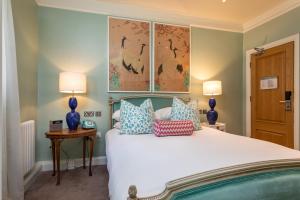 a bedroom with a large white bed with blue lamps at Roslin Beach Hotel in Southend-on-Sea