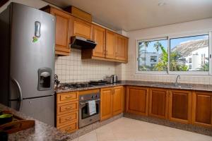 La cuisine est équipée d'armoires en bois et d'un réfrigérateur en acier inoxydable. dans l'établissement Spacious BeachView Condo Marina - Families Only, à Agadir