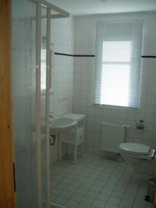 a white bathroom with a sink and a toilet at Ferien unterm Reet in Prerow