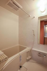 a bathroom with a bath tub and a mirror at One-asakusa in Tokyo