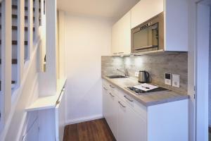 una pequeña cocina con armarios blancos y fregadero en Haus-Amici, en Tinnum
