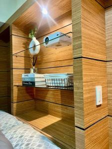 a bedroom with a wooden wall with a bed and a lamp at NAIA T3 -10 PERCENT OFF JUNE GRADUATION PROMO- Fully Interiored 1 BR Unit in Manila