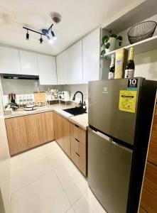a kitchen with a stainless steel refrigerator and wooden cabinets at NAIA T3 -10 PERCENT OFF JUNE GRADUATION PROMO- Fully Interiored 1 BR Unit in Manila