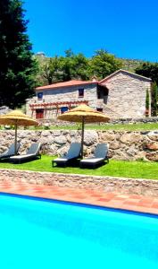 two chairs and umbrellas next to a swimming pool at Casas da Fonte - Turismo Rural in Vila Verde