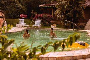 two children swimming in a swimming pool with a woman at Aldeia Gaia Chalés in Teresópolis +118 photos