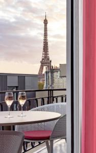 two glasses of wine on a balcony with the eiffel tower at Villa Marquis Member of Meliá Collection in Paris