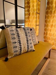 dos almohadas sentadas en la parte superior de un banco amarillo en Nuevo Moderno Apartamento de Lujo, en Sevilla