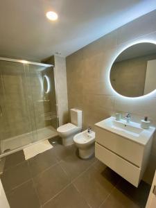 y baño con aseo, lavabo y ducha. en Nuevo Moderno Apartamento de Lujo en Sevilla