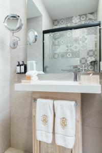 łazienka z umywalką i ręcznikami na ladzie w obiekcie voco Royalty Puebla Downtown w mieście Puebla