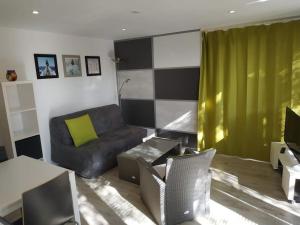 a living room with a couch and a green curtain at Studio jacuzzi privé à 8 min à pied de la plage in La Ciotat