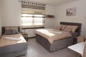 Un dormitorio con dos camas y una ventana. en Apartman Mila, en Županja