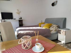 a room with a bed and a table with a cup of coffee at Apartman Harmony 2 in Banja Koviljača