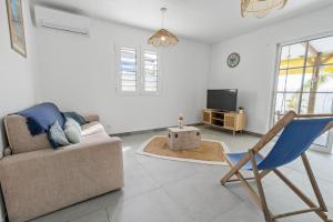Una sala de estar con un sofá y un televisor. en Villa Kaz Kreyol, en Les Anses-dʼArlet