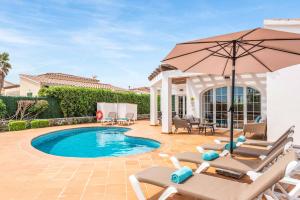 a swimming pool with chairs and an umbrella at Villa Sara Porter in Cala'n Porter
