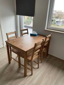 una mesa de madera y sillas en una habitación con ventana en Appartement Brussels Airport, en Machelen