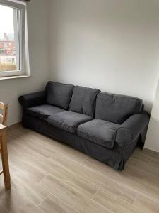 - un canapé noir dans le salon doté d'une fenêtre dans l'établissement Appartement Brussels Airport, à Machelen
