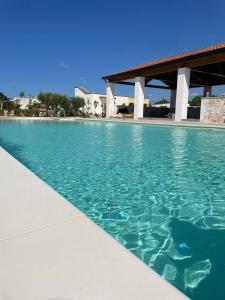 - une piscine d'eau turquoise à côté d'un bâtiment dans l'établissement Boara Resort, à Mottola