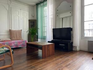a living room with a television and a couch at Loft de la plage Concurrence in La Rochelle