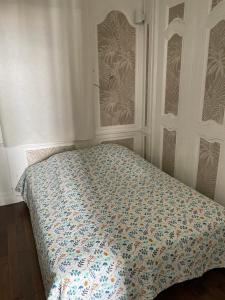 a bedroom with a bed with a floral comforter at Loft de la plage Concurrence in La Rochelle