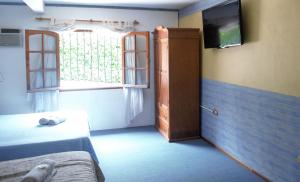 a room with a bed and a television on a wall at Hotel de France Rio Ceballos in Río Ceballos