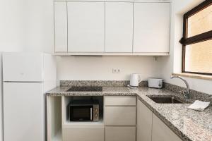 a white kitchen with a sink and a microwave at A48 - Windmill 1 Bed Apartment in Odiaxere in Odiáxere