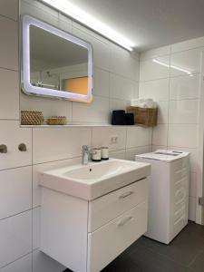 W białej łazience znajduje się umywalka i lustro. w obiekcie Stylische Wohnung im Herzen von Bregenz mit privatem Parkplatz w Bregencji