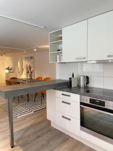 a kitchen with white cabinets and a dining table at Stylische Wohnung im Herzen von Bregenz mit privatem Parkplatz in Bregenz