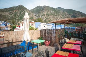 a patio with tables and chairs with mountains in the background at Dar Chourafa Riad in Chefchaouen