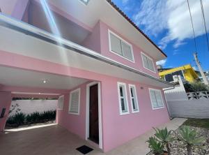 a pink and white house with a driveway at 411- Casa para 8 pessoas 20 metros da Praia Central em Bombinhas in Bombinhas