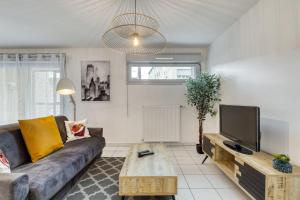 ein Wohnzimmer mit einem Sofa und einem TV in der Unterkunft ZenBNB / Stella / Proche Gare / Garage / Wifi / in Annemasse