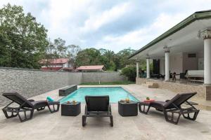une piscine avec deux chaises et une piscine dans l'établissement Villa-Aquaterra-Hideaway-piscine-Barbecue, à Matoury