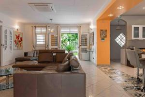 uma sala de estar com um sofá castanho e uma cozinha em Villa-Aquaterra-Hideaway-piscine-Barbecue em Matoury