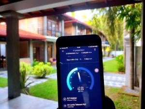 a person holding a cell phone in front of a house at Ravan Resort Tangalle in Tangalle