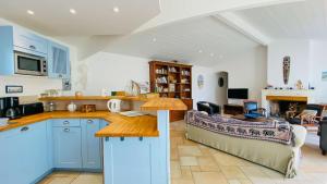 kuchnia z niebieskimi szafkami i salon w obiekcie Villa à proximité de la plage et des commerces w mieście La Couarde-sur-Mer