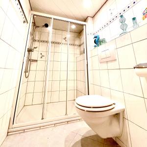 a white bathroom with a shower and a toilet at Guest Apartment Seeland 