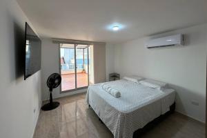 a white bedroom with a bed and a window at Apartamento Victoria in Puerto Colombia