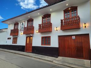 a white building with wooden doors and windows at Casa Kuelap Hostal in Chachapoyas