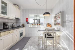 a kitchen with white cabinets and a table and chairs at FURADOURO - Vista dos Pinhais - apart 2 quartos a 100 metros da praia do Furadouro in Ovar